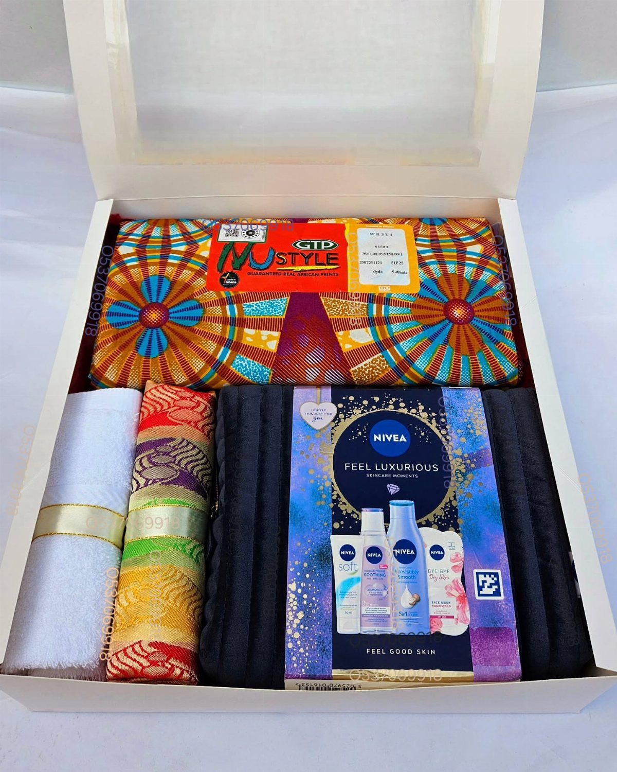 A white gift box filled with colorful towels and a Nivea skincare set.