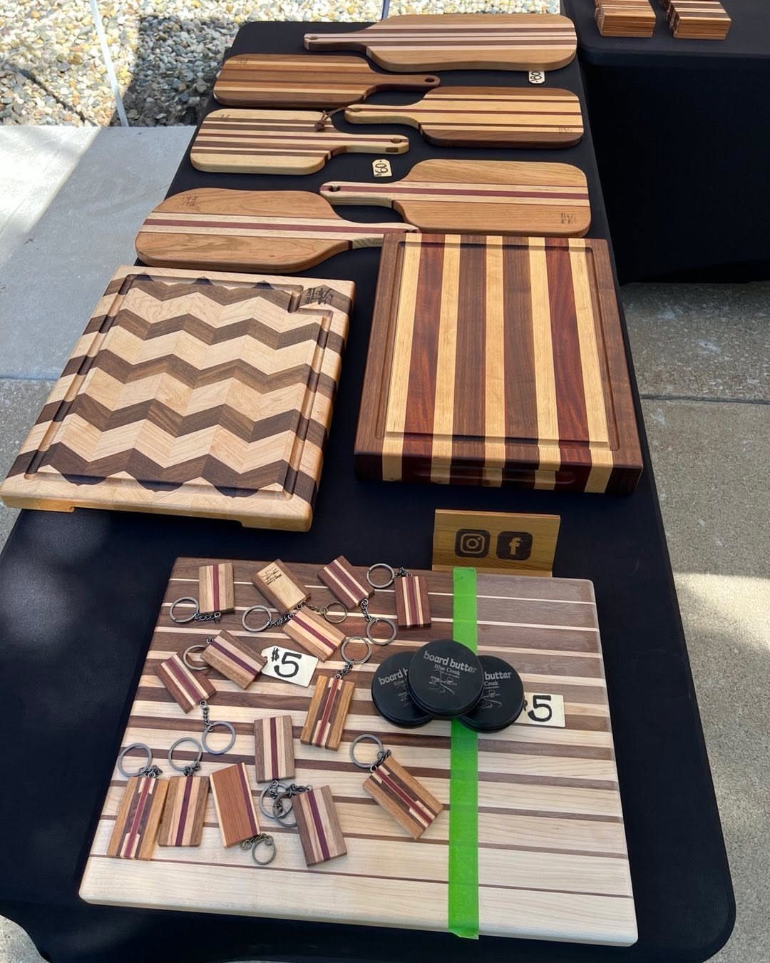 Various wooden cutting boards with different grain patterns displayed on a black table.