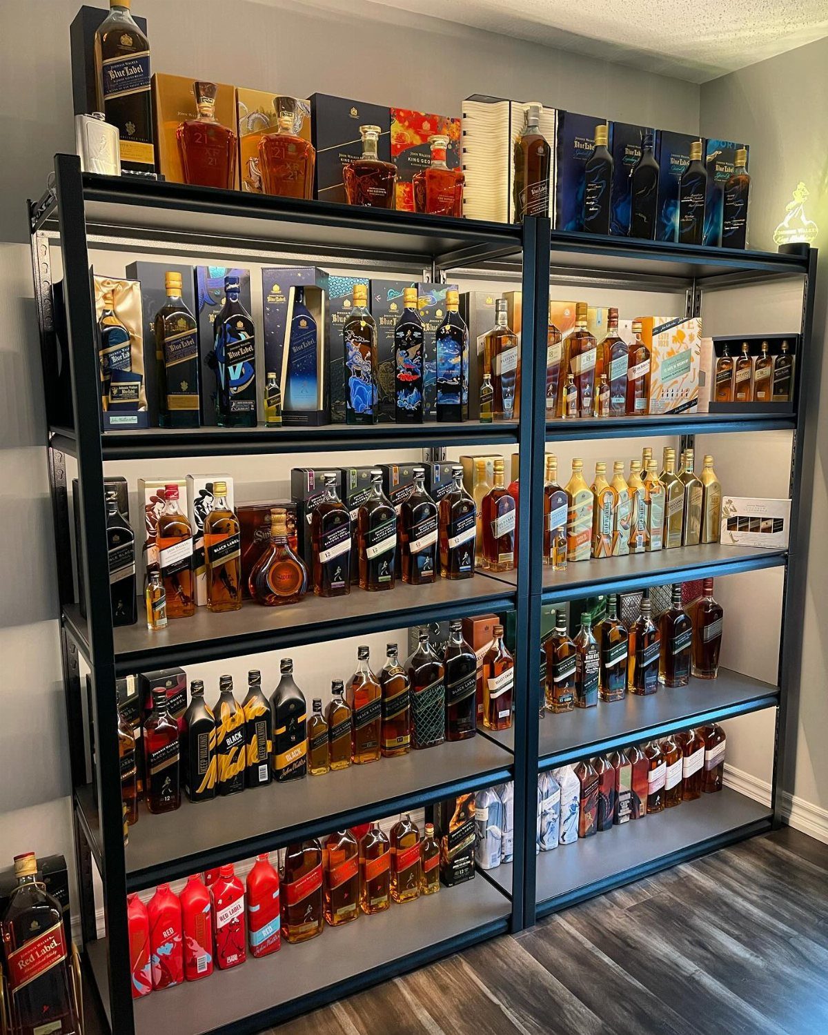 Numerous bottles of whiskey and spirits arranged on large black metal shelves.