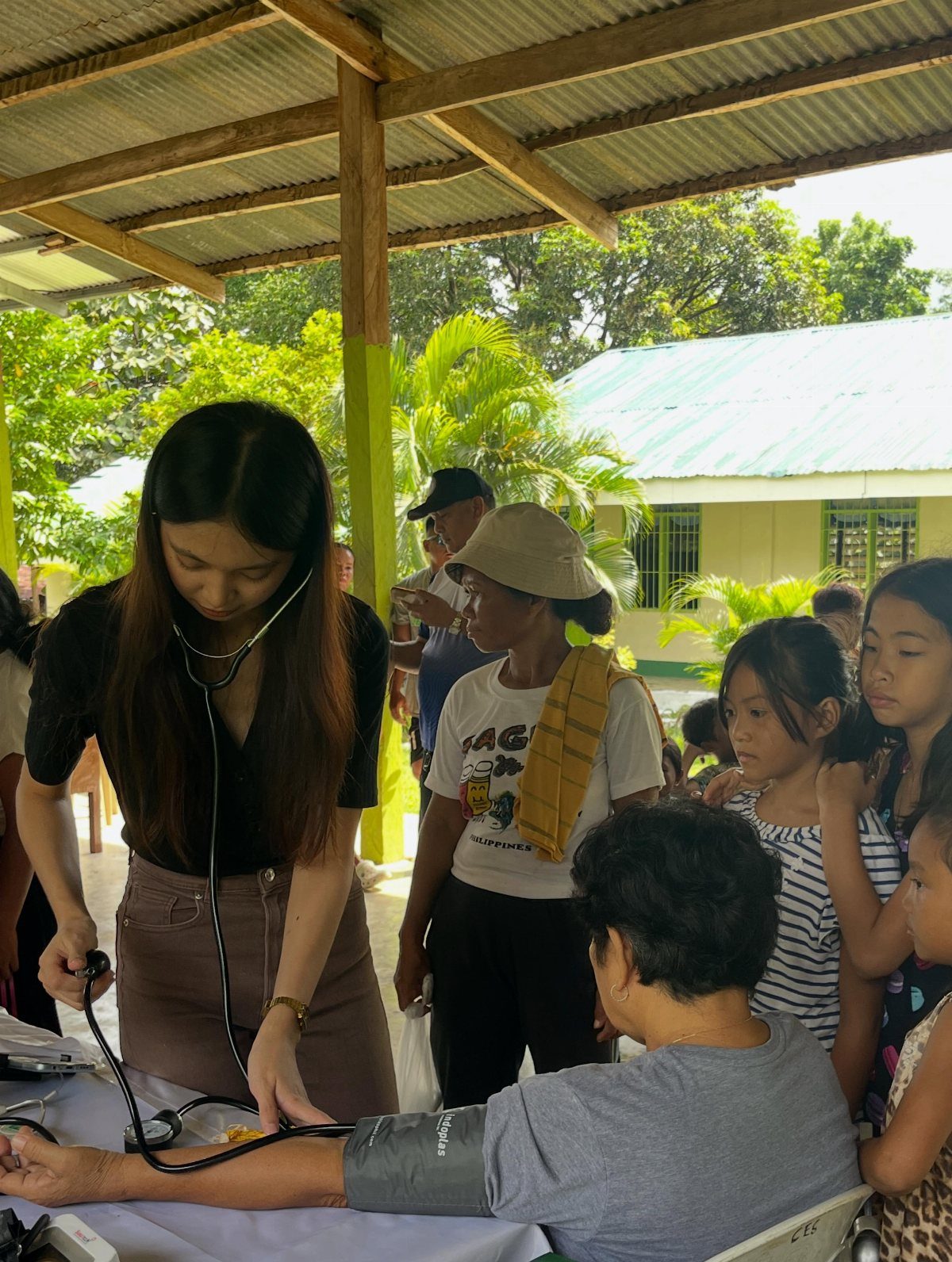 A young woman uses a stethoscope to perform a medical check on an elderly woman.