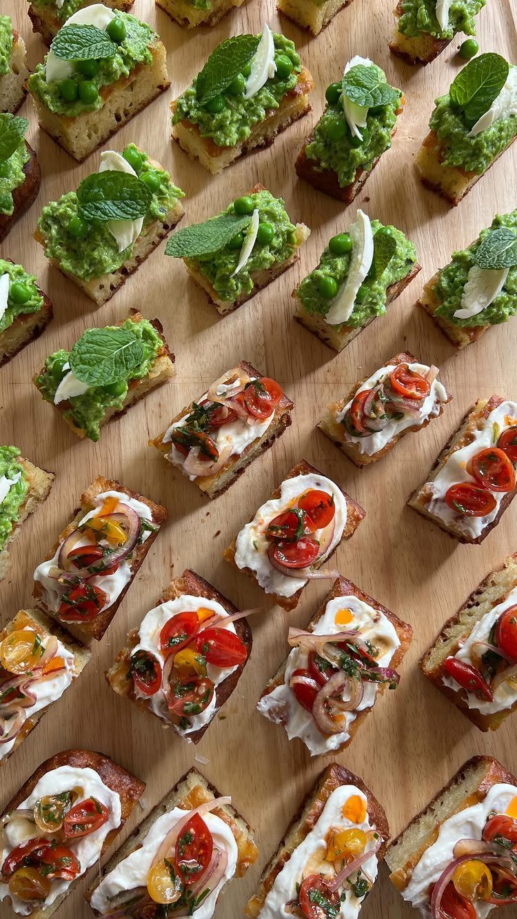 Various small appetizers like tomato bruschetta and pea puree crostini on a wooden board.