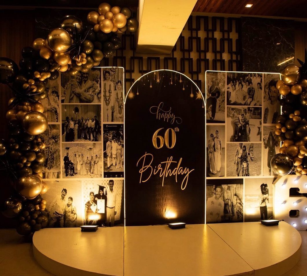 Birthday stage setup with vintage photo collages, gold balloons, and a black arched backdrop.