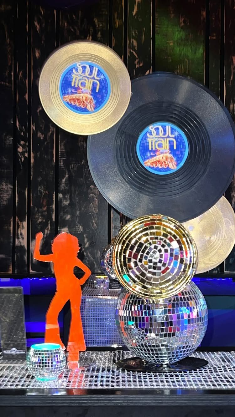 Disco decorations including vinyl records, sparkling disco balls, and a dancing silhouette on a dark background.