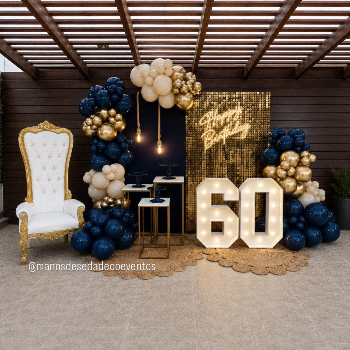 Large marquee light-up numbers 60 surrounded by navy and gold balloons and a white throne chair.