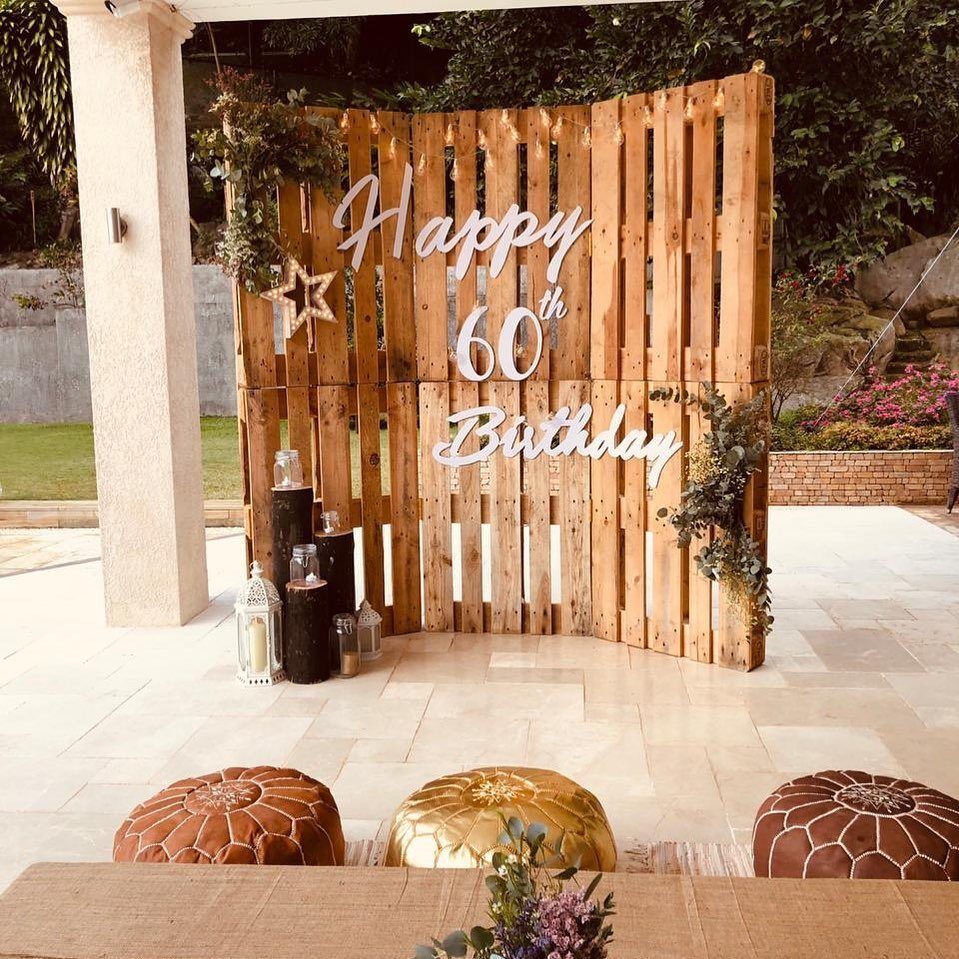 Wooden pallet backdrop with Happy 60th Birthday sign and decorative lanterns on a patio.