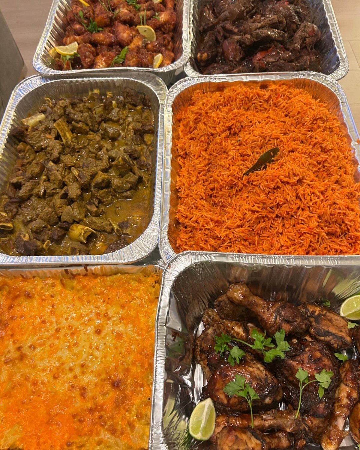 Various trays of cooked meat, rice, and pasta dishes arranged together for a meal.