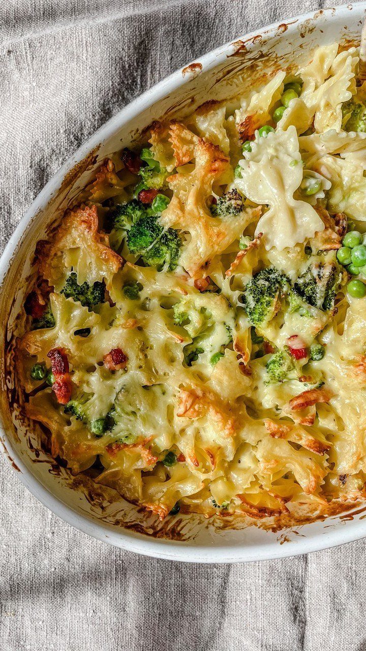 Cheesy pasta bake with broccoli and farfalle noodles in a white ceramic dish.