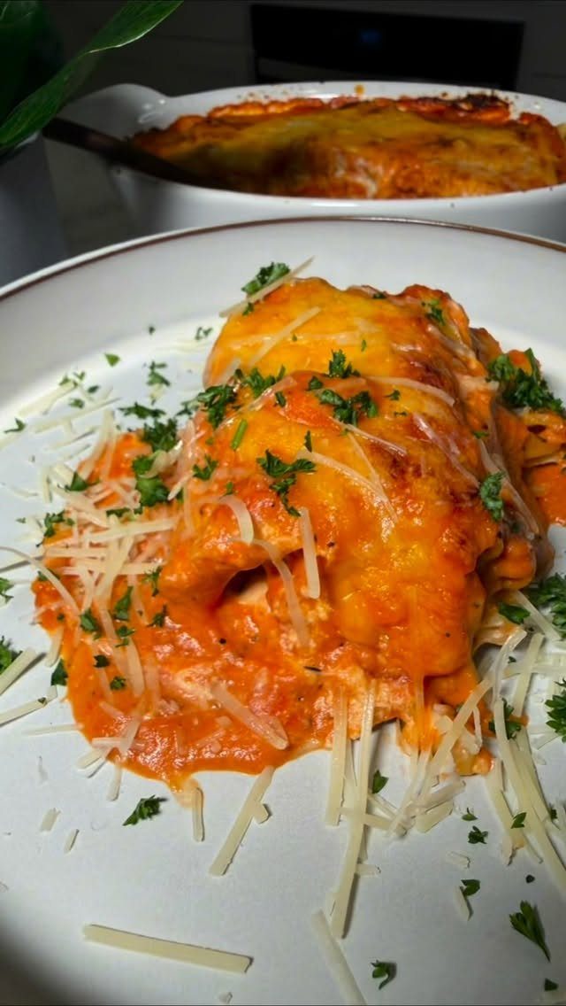 Creamy orange pasta topped with shredded parmesan cheese and fresh parsley on a white plate.