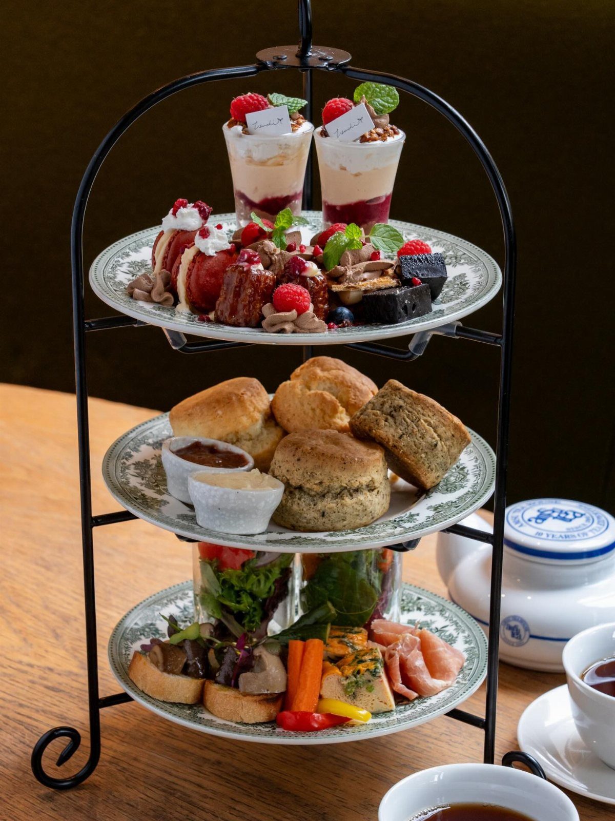 A three-tiered stand filled with afternoon tea delicacies including scones, desserts, and savory sandwiches.
