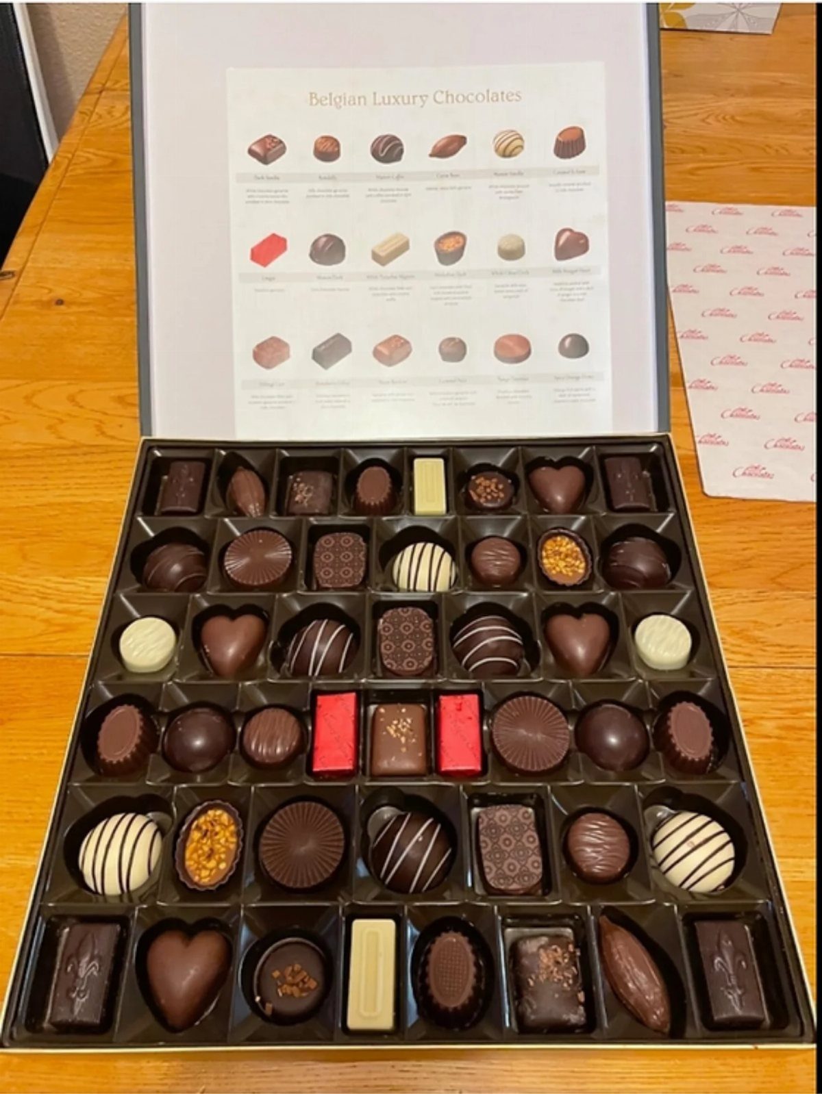 An open box filled with an assortment of various Belgian luxury chocolates.