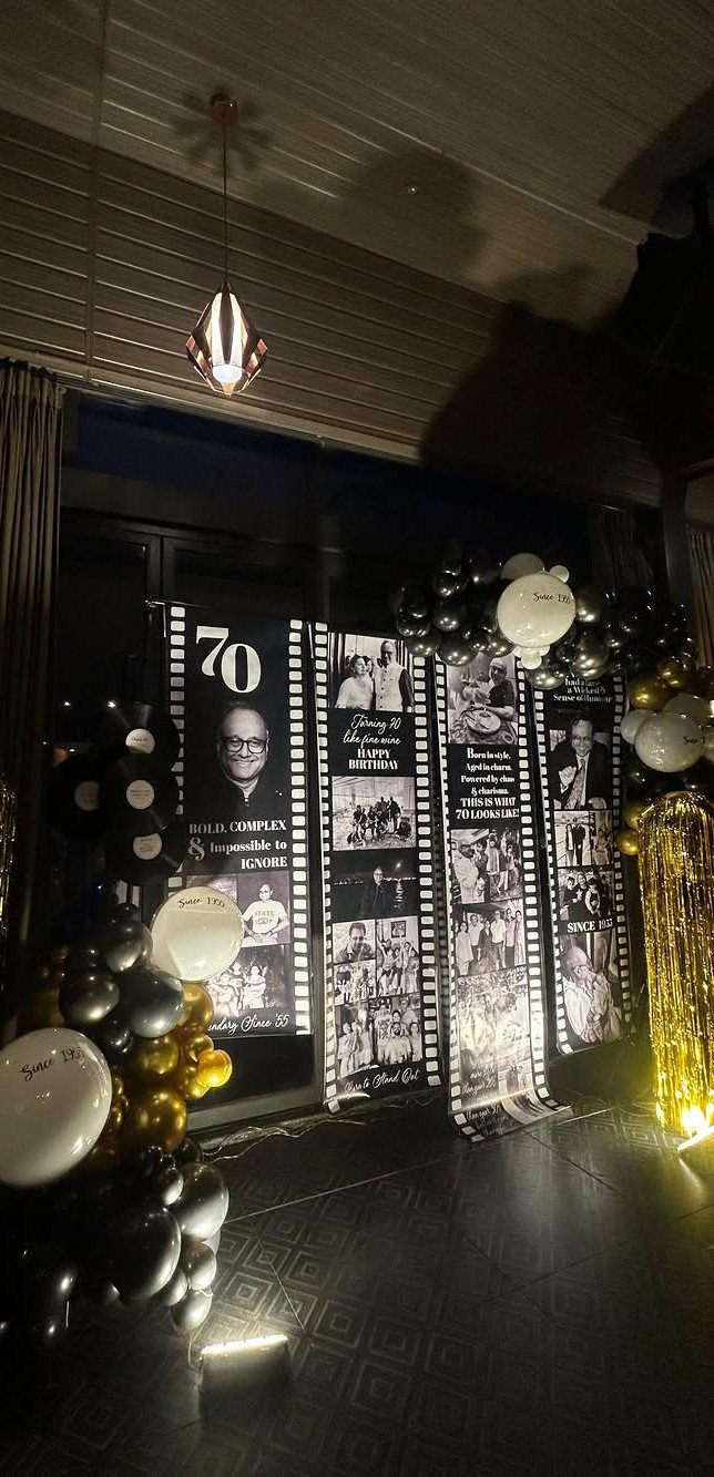 Black and gold balloons surround tall birthday banners featuring vintage photos and the number 70.