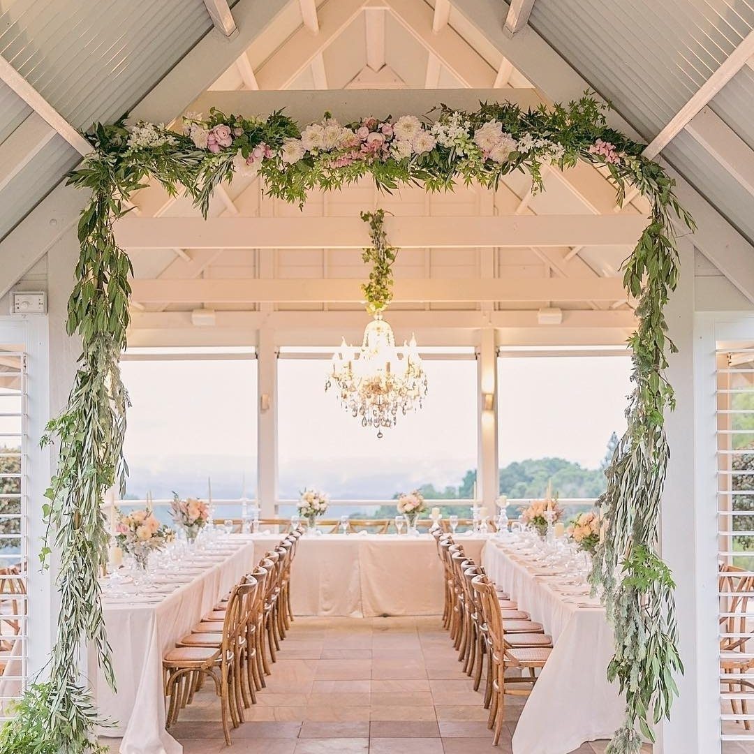 Elegant long dining tables set for a formal celebration under a white pavilion with floral decorations.