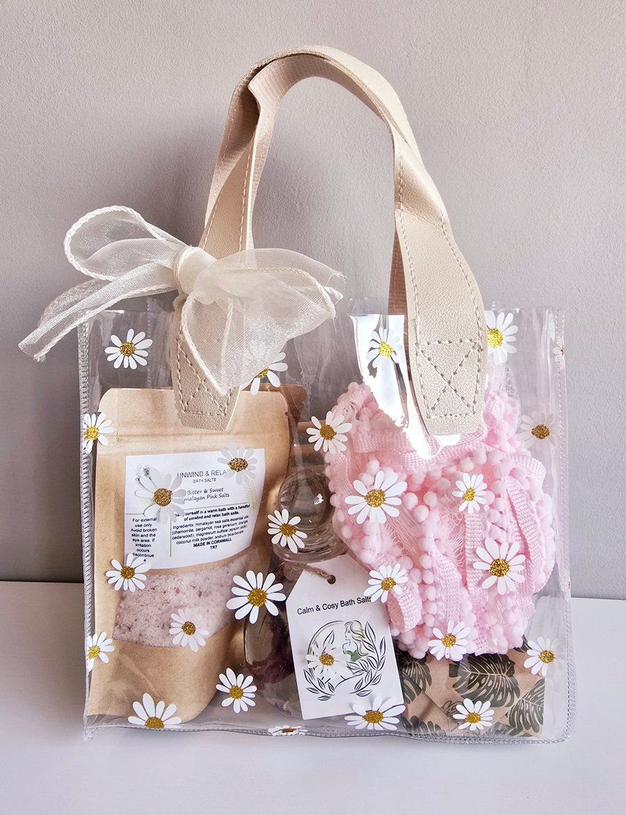 A clear tote bag filled with pink knitted items and botanical themed gift sets.