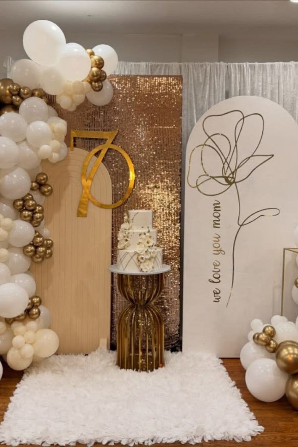 A 70th birthday celebration setup with a cake, gold balloons, and a large number 70.