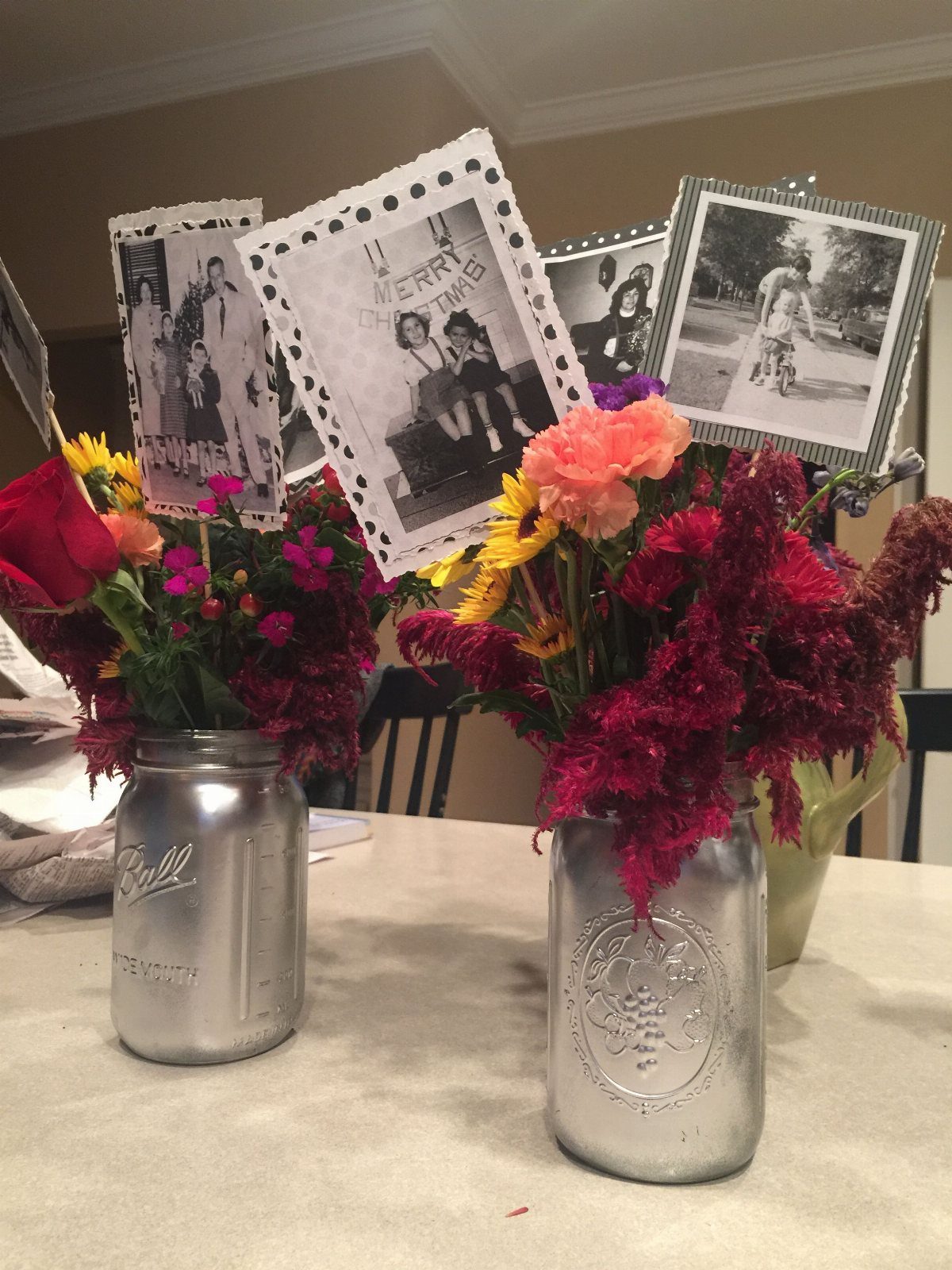 Silver mason jar vases with colorful flowers and vintage black and white photographs.