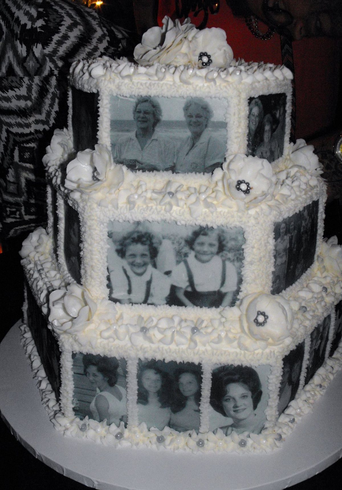 A three-tiered white cake decorated with edible black and white vintage photographs.