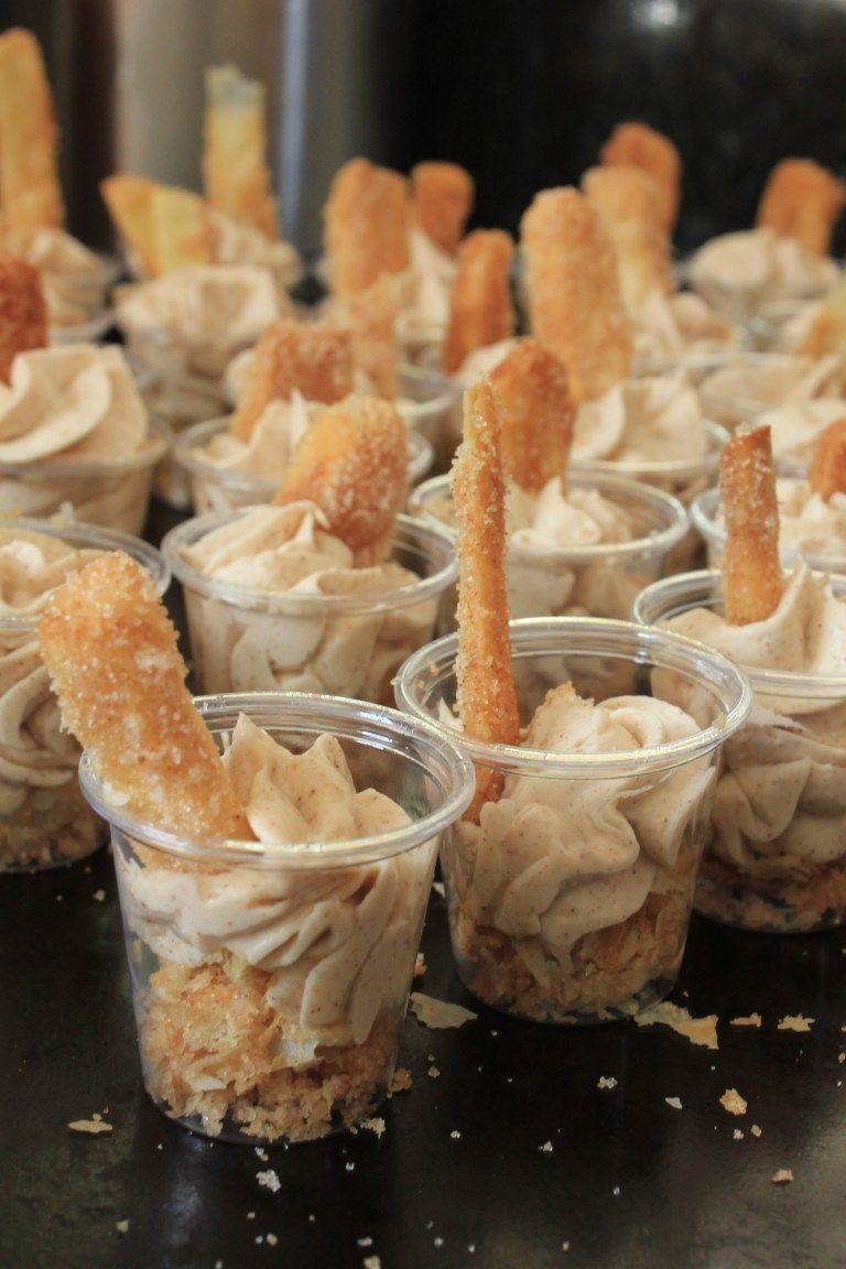 Small plastic cups filled with creamy mousse and topped with long sugar-coated biscuit sticks.