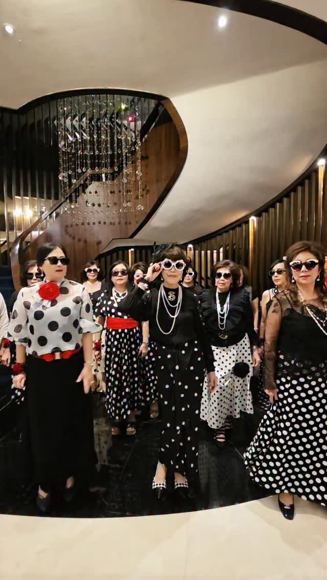 Group of women in matching black and white polka dot clothing posing together indoors.