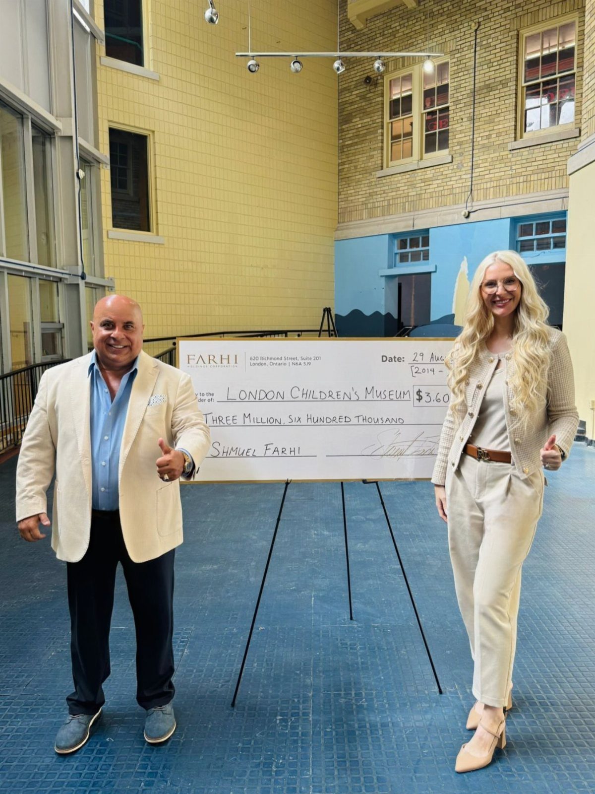 A man and woman posing with a large ceremonial donation check for a children's museum.