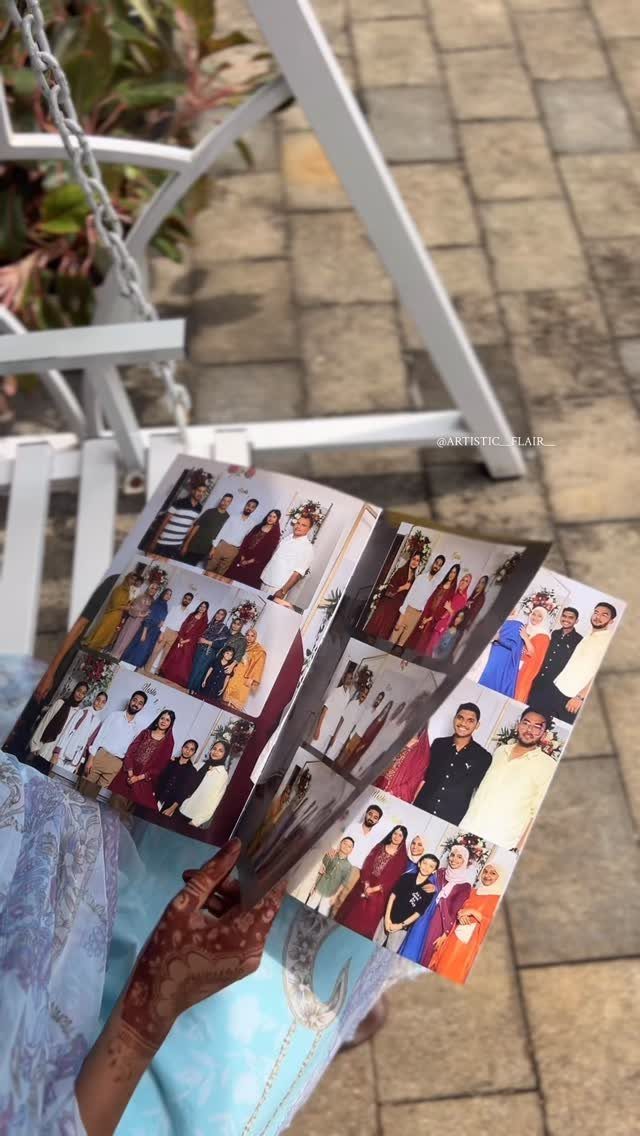 Hands holding an open personalized photo album filled with many colorful family portrait photographs.