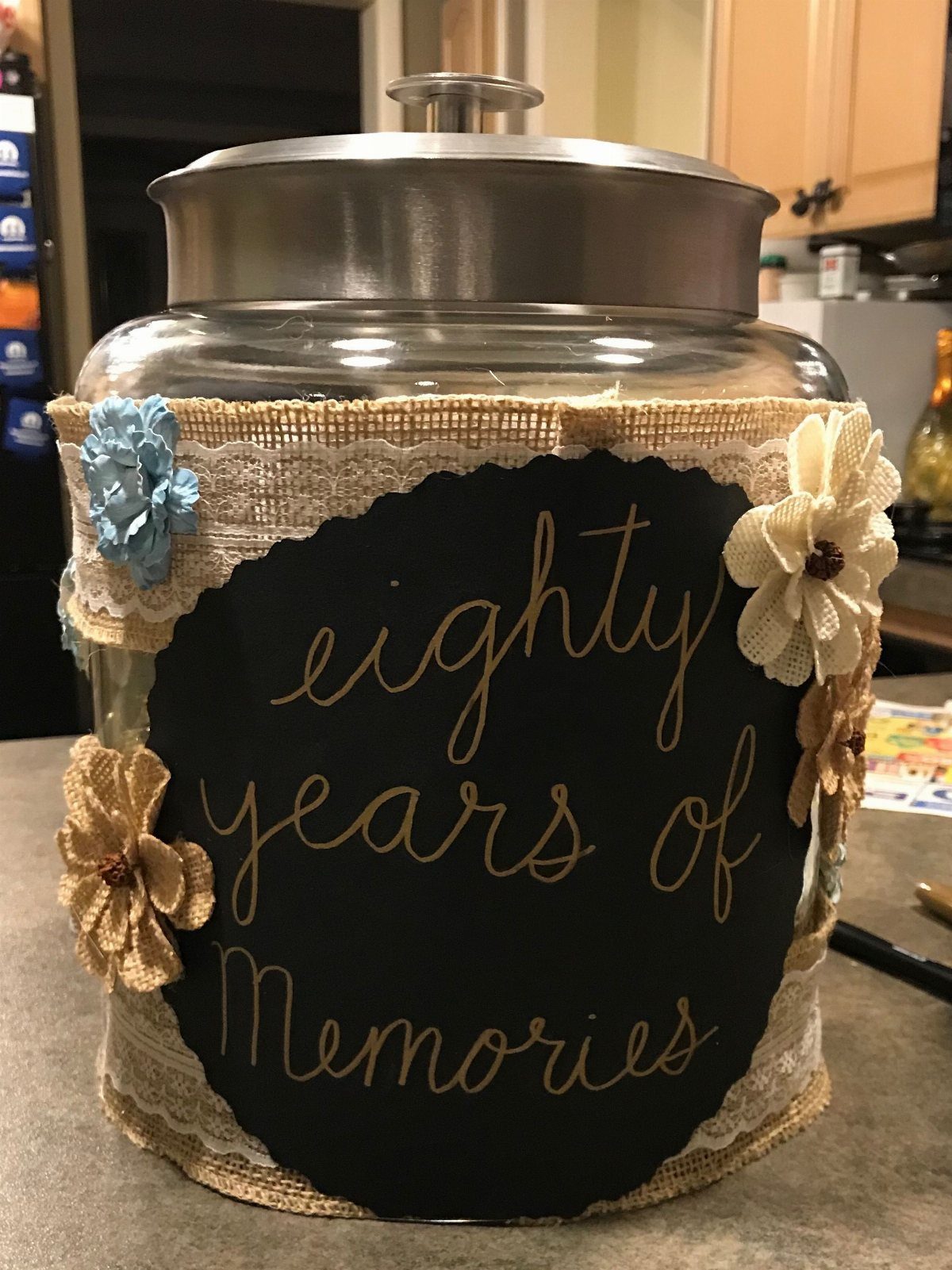 A decorated glass jar with a chalkboard sign that says eighty years of Memories.