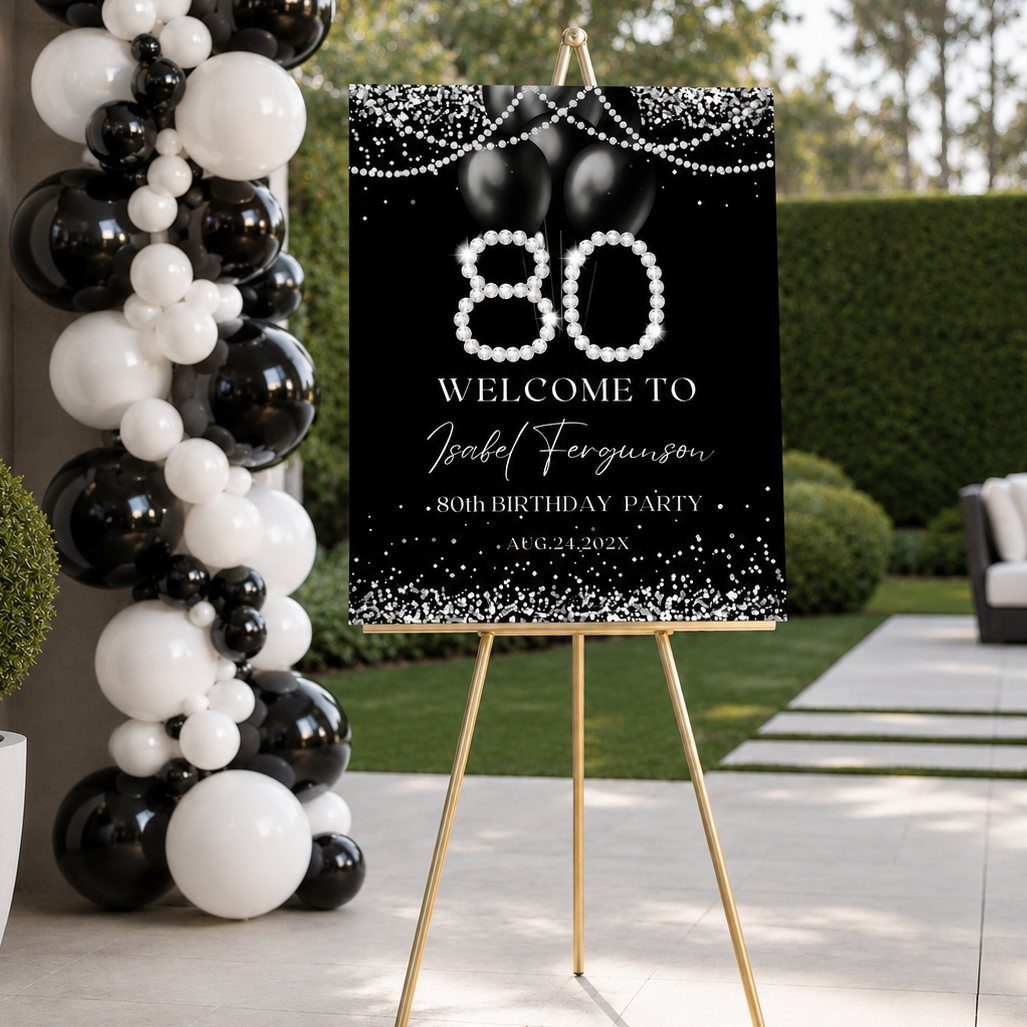 Black and white balloon arch next to an 80th birthday welcome sign on a gold easel.