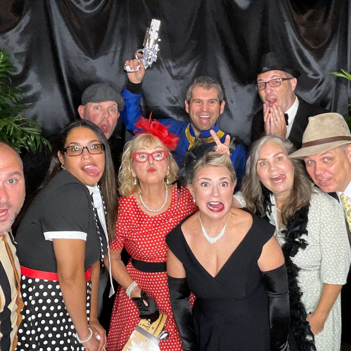 Group of people dressed in 1940s themed costumes posing playfully for a photo.