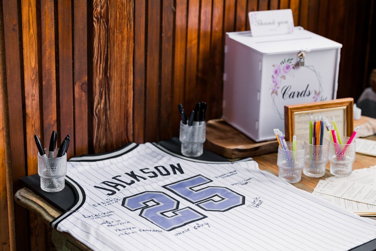 A white sports jersey with handwritten messages and markers on a wooden table.
