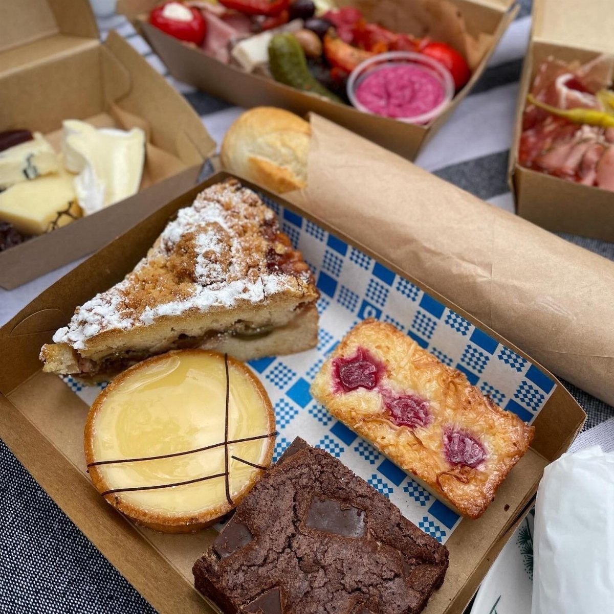 Assorted desserts including cake, tart, brownie, and fruit bar in a cardboard tray.