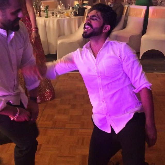 Two men dancing energetically on a wooden floor under pink lighting in a banquet hall.