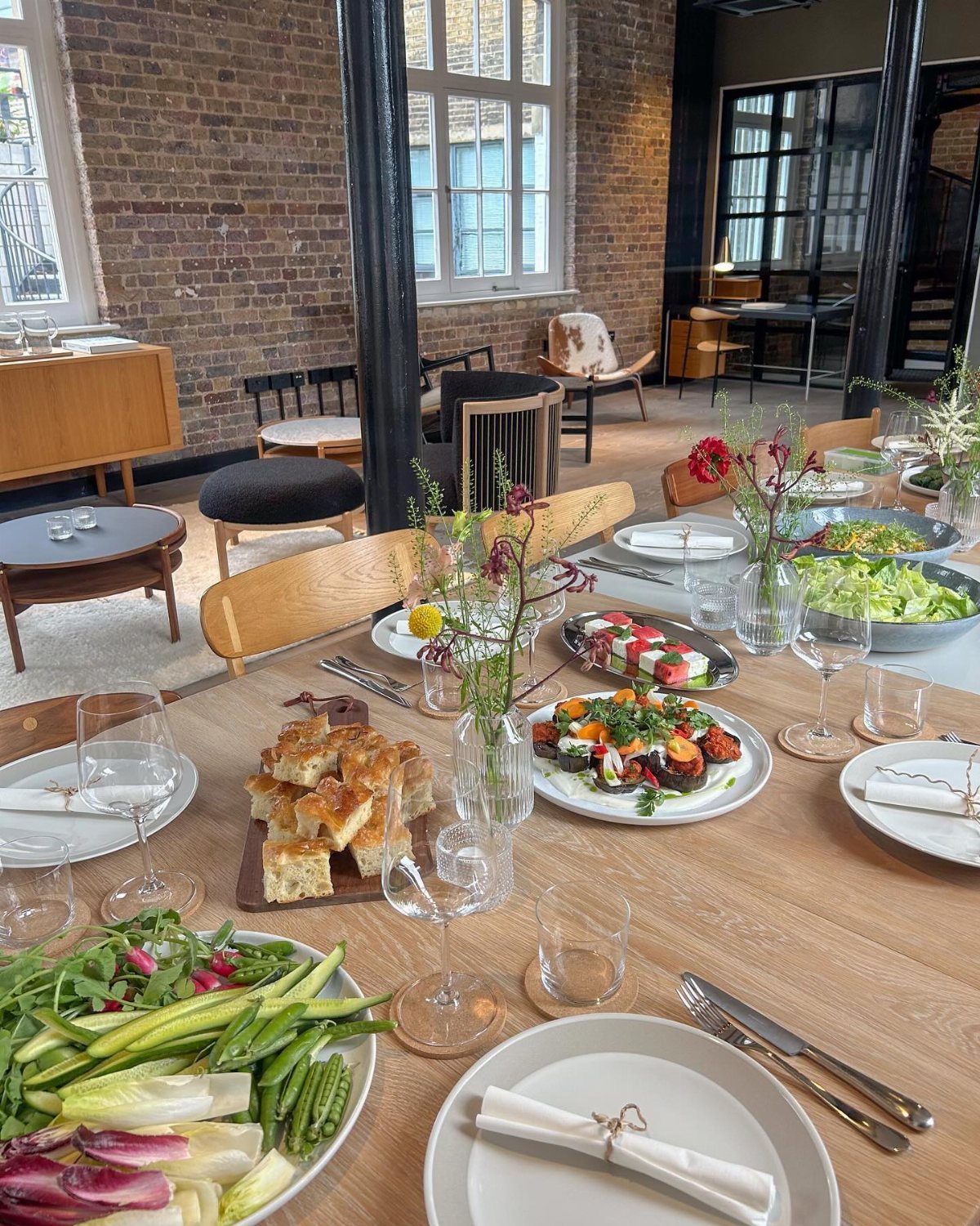 A long wooden dining table set with various seasonal dishes and floral arrangements.