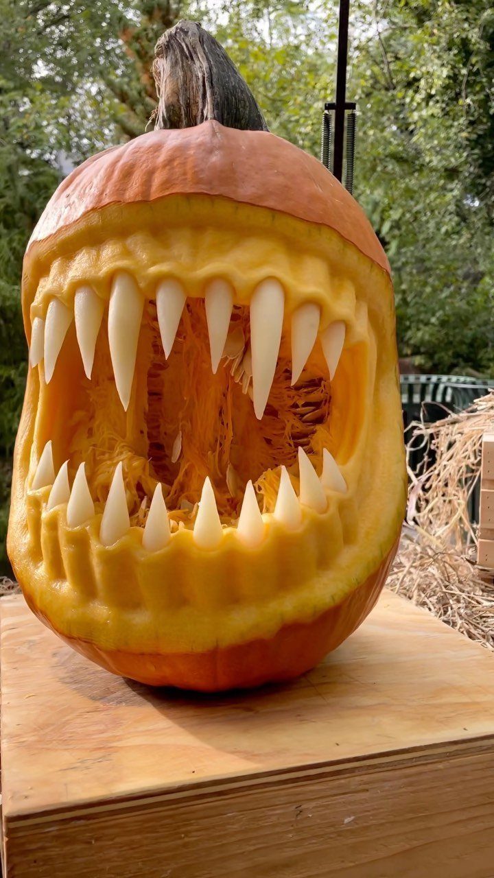 A large orange pumpkin carved with sharp white teeth and a wide mouth.