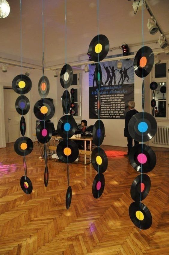 Vinyl records with colorful labels hanging from the ceiling over a wooden floor.