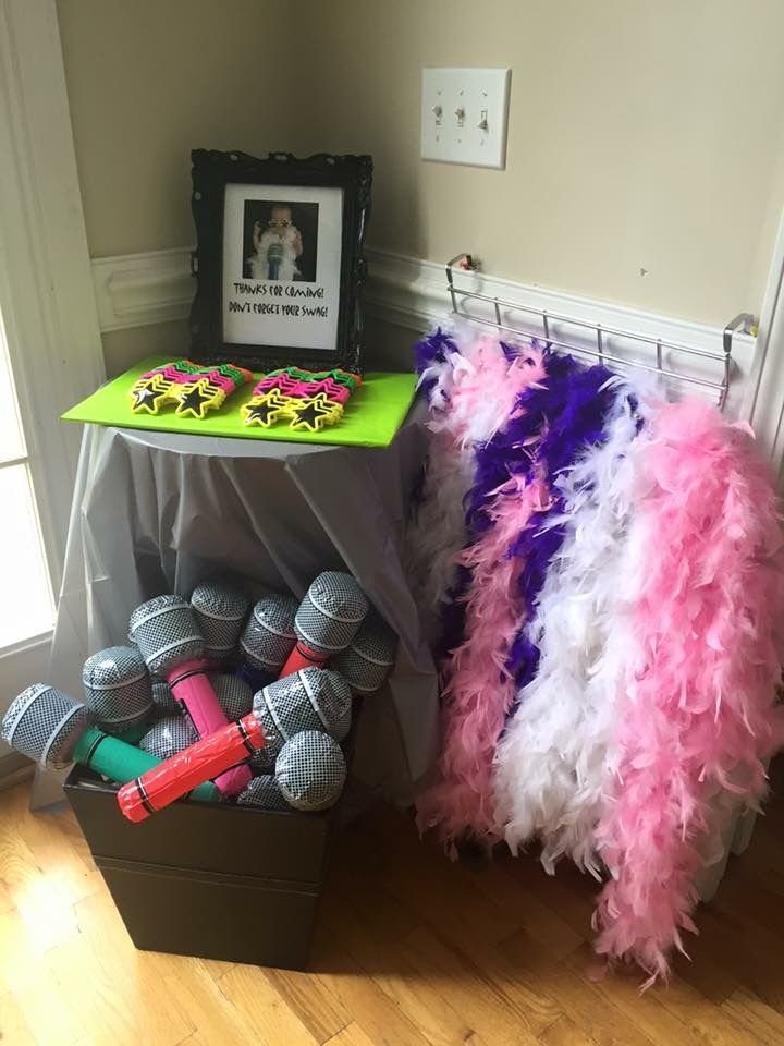 Microphones in a bin next to a table with decorations and colorful feather boas.