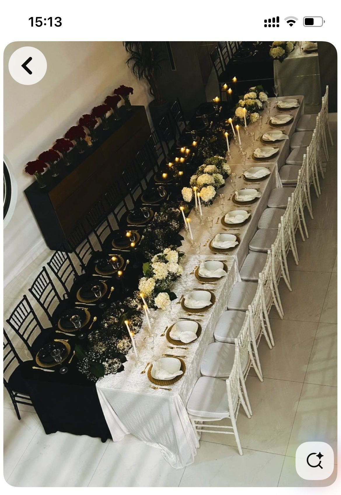 An elegantly set long dining table with white flowers, candles, and gold-rimmed plates.