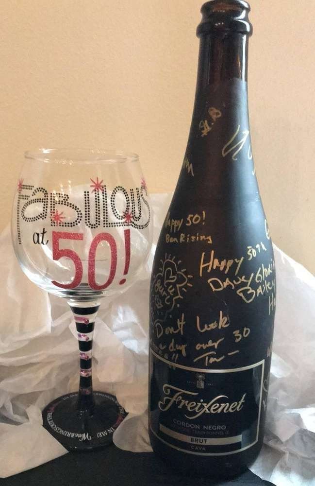 A wine glass and Freixenet bottle decorated with celebratory messages for a 50th birthday.