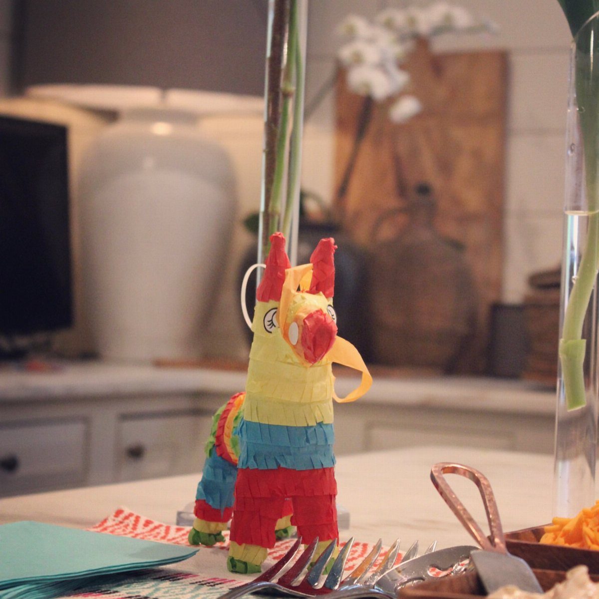 A colorful donkey piñata standing on a white table in a kitchen setting.