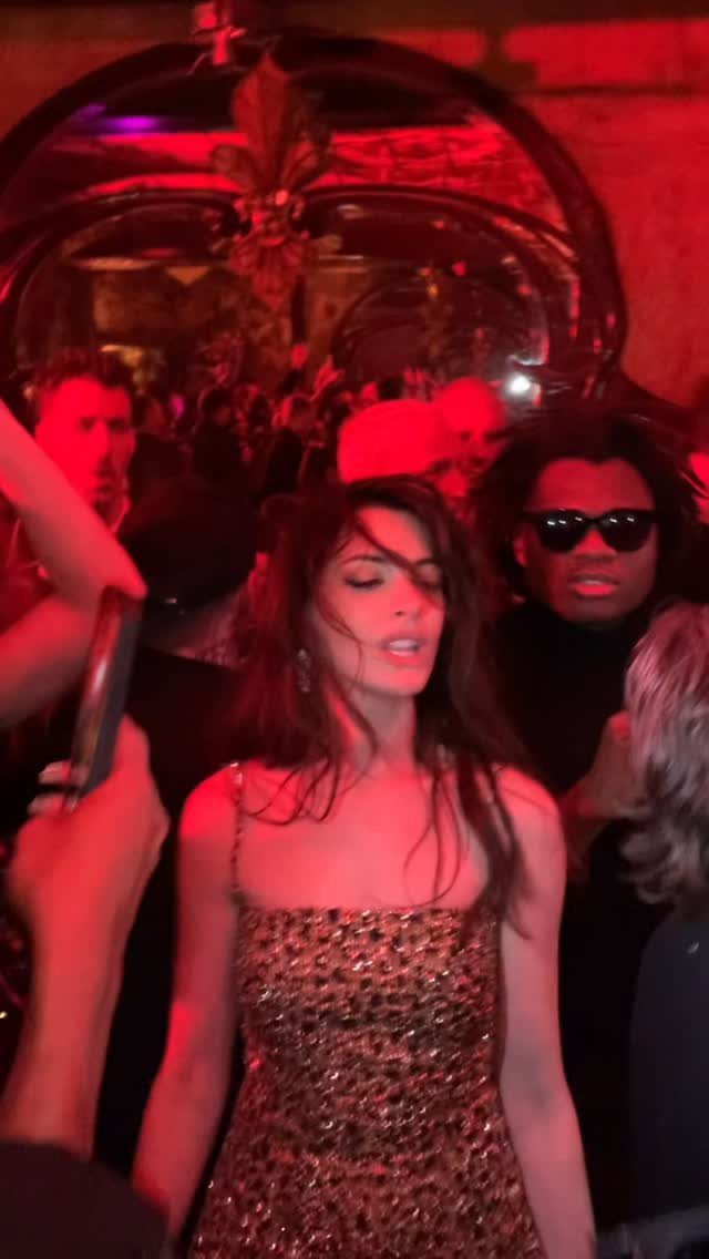 A woman in a gold sequined dress dancing in a red-lit nightclub.