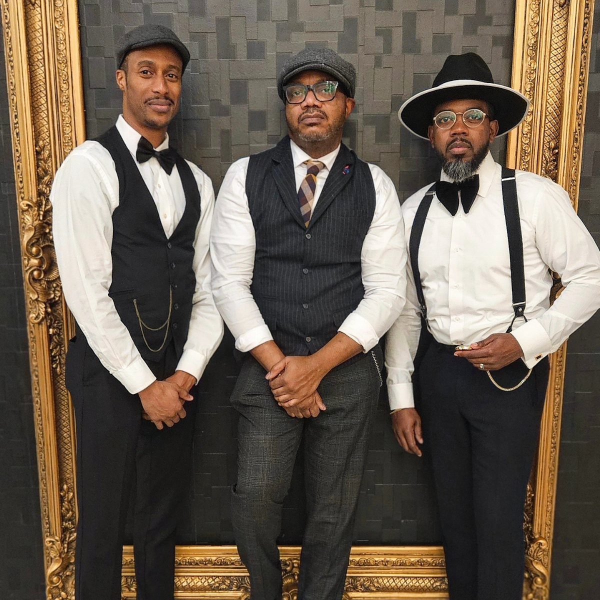 Three men dressed in vintage 1920s style clothing posing together.