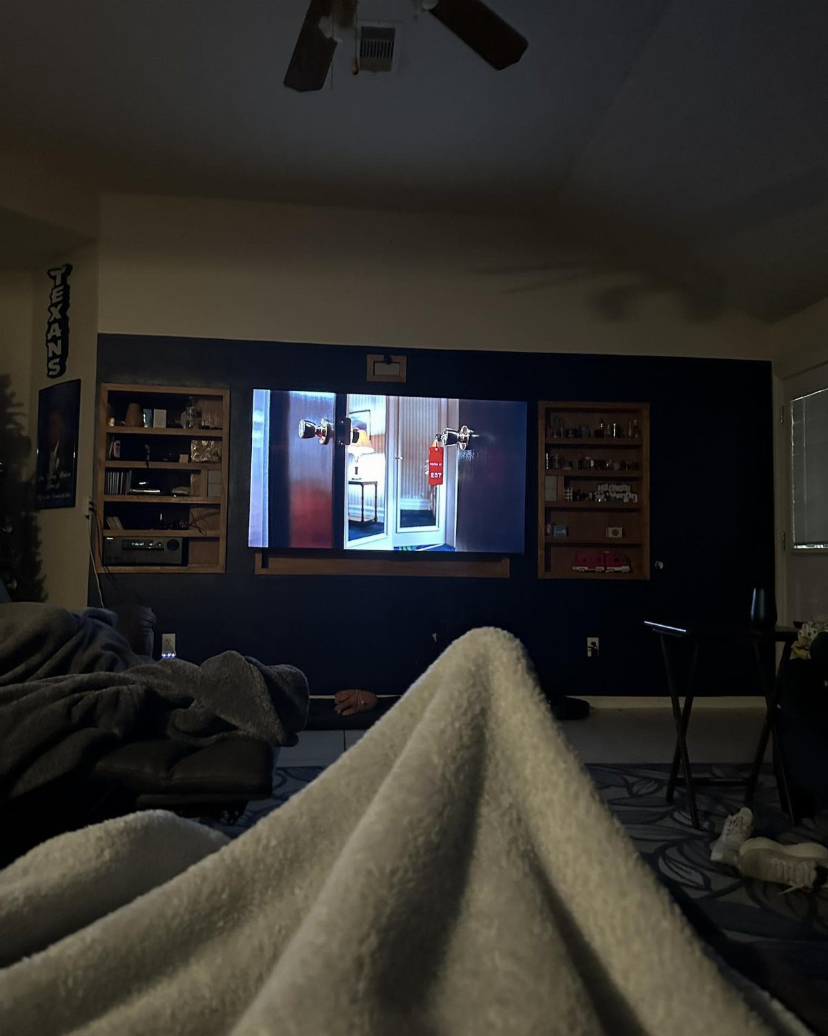 A television playing a movie in a dark living room with a blue wall.