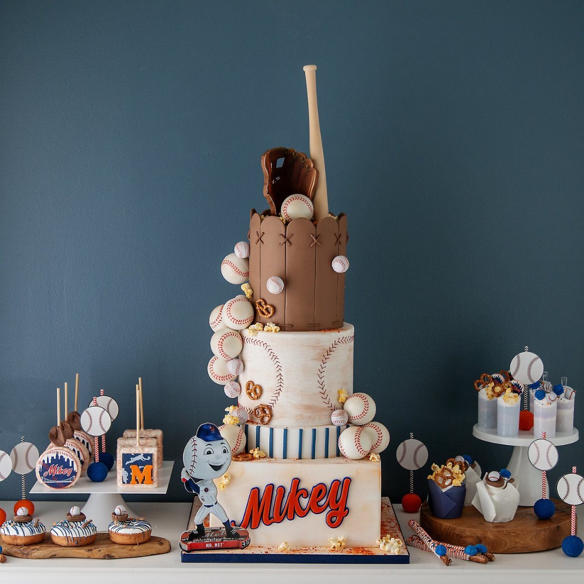 A large multi-tiered baseball themed birthday cake decorated with edible baseballs and a bat.
