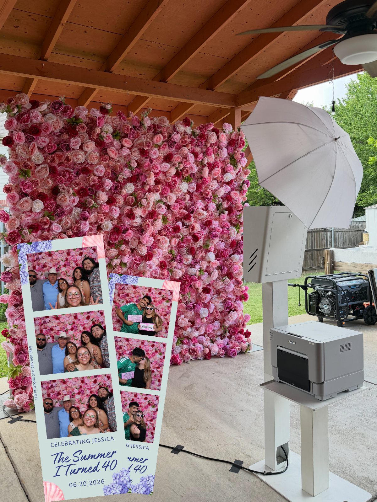 Photo booth setup with a pink flower wall, lighting equipment, and printed photo strips.
