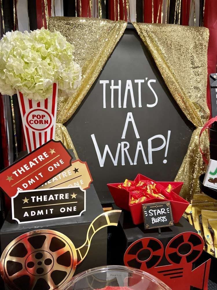 Movie themed party decorations including a chalkboard sign, popcorn containers, and theater tickets.