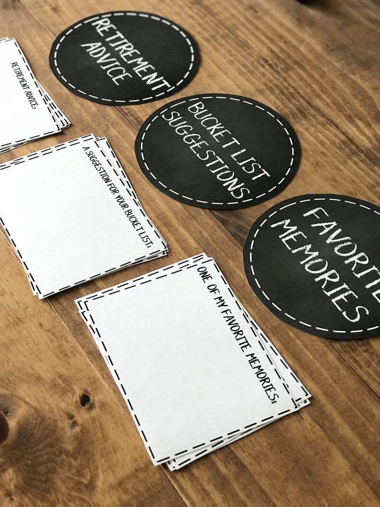 Black and white printed cards and circular tags with retirement themed prompts on wood.