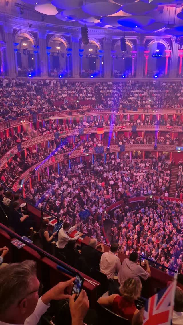 Crowd enjoying a concert with colorful lights and ornate architecture.