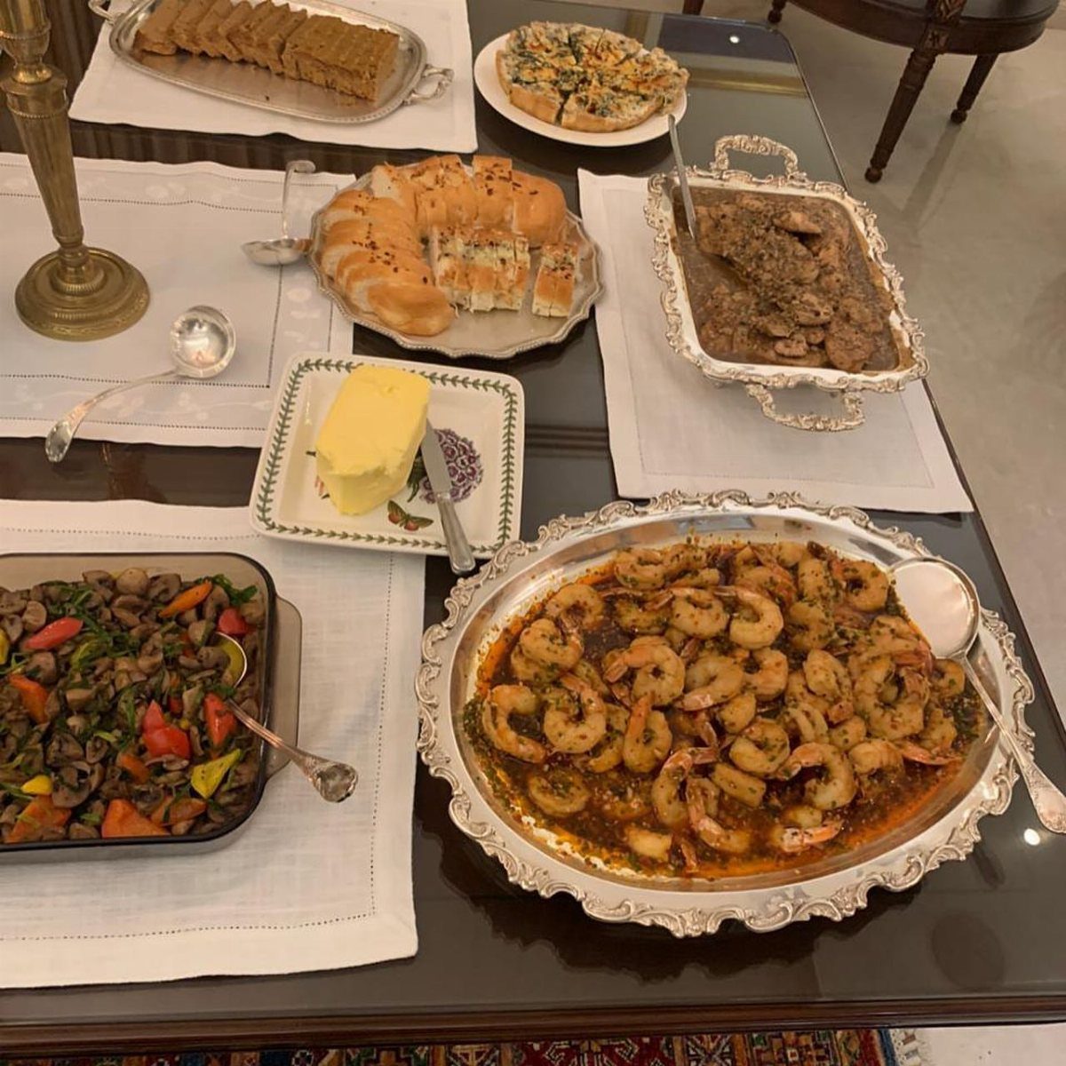 Various savory and sweet dishes served on silver platters across a dining table.