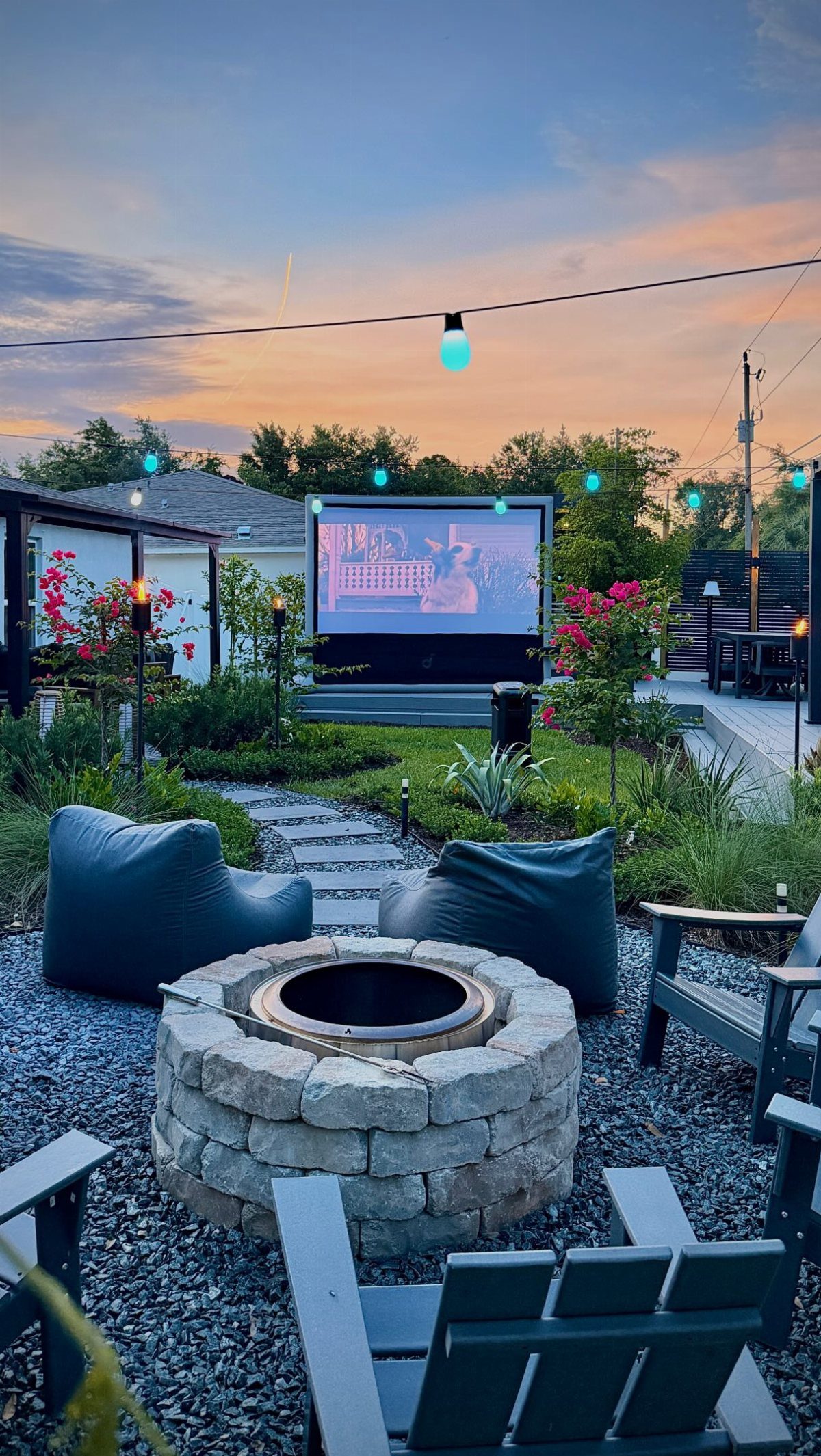 Outdoor movie setup with a fire pit and large screen.