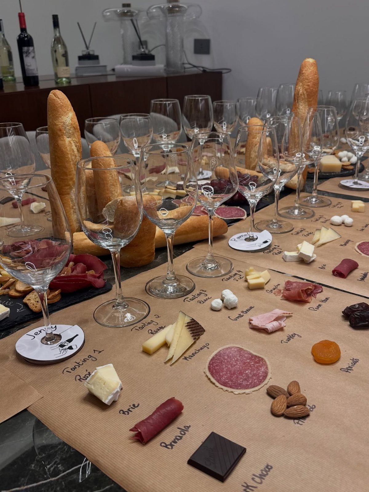 Table arranged for a wine tasting with glasses, cheeses, and meats.