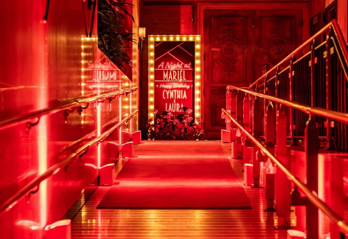 Red carpet walkway with glowing lights and gold railings leading to a sign.