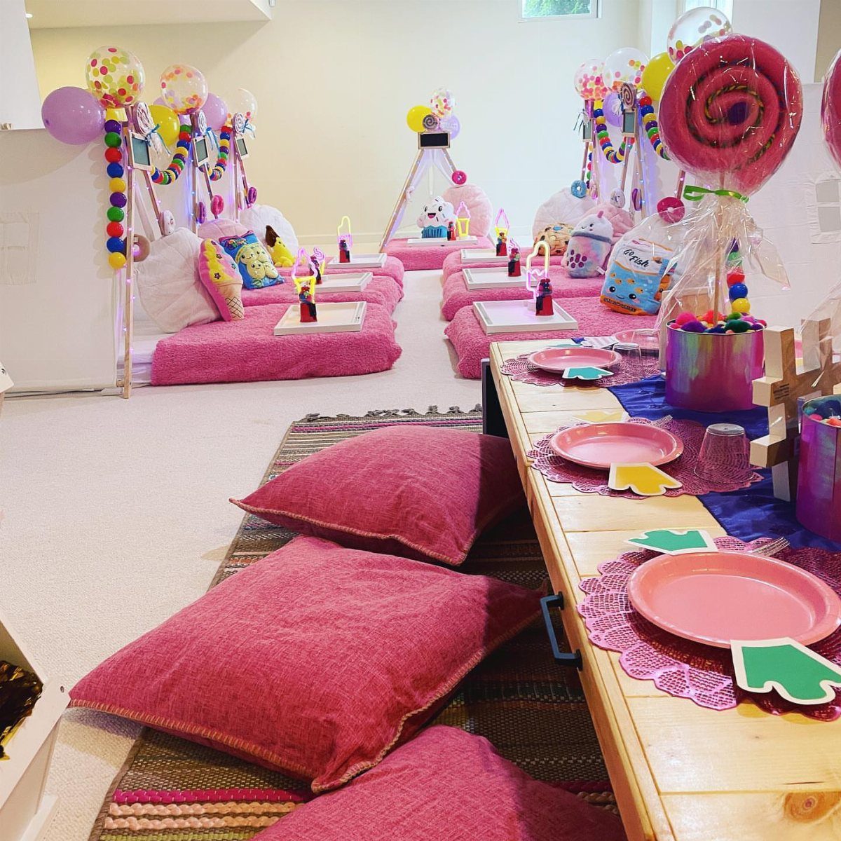 Pink floor mattresses and decorated tables set up for a festive indoor slumber party.